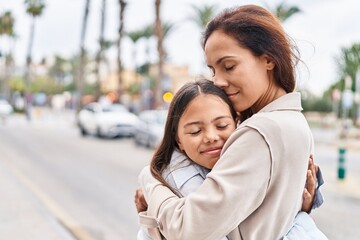 Woman and girl mother and daughter hugging each other at street