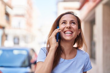 Young woman smiling confident talking on the smartphone at street