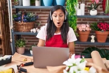 Young hispanic woman working at florist shop doing video call scared and amazed with open mouth for surprise, disbelief face