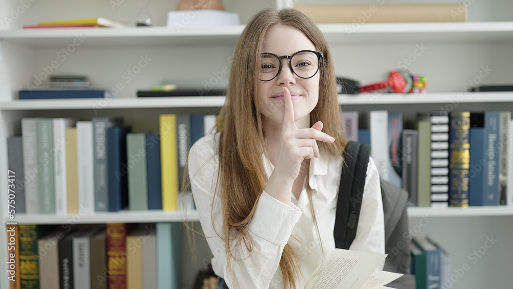 Poster young blonde woman student reading book doing silence gesture at university classroom