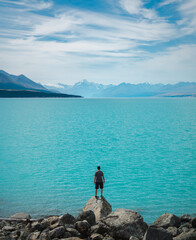 Fototapeta premium Mensch auf einem Felsen mit Aussicht über den türkisen Lake Pukaki mit Blick auf den Mount Cook in Neuseeland.