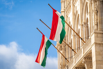 Hungary National flags. Two Hungarian flags on flagpole hanging on a building against the blue sky.
