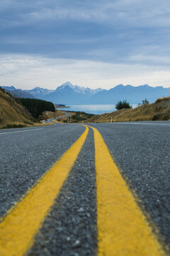 Stra&szlig;e mit gelben Streifen und Asphalt in Neuseeland mit Mt Cook im Hintergrund im Nationalpark.