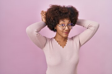 Young african american woman standing over pink background doing bunny ears gesture with hands...