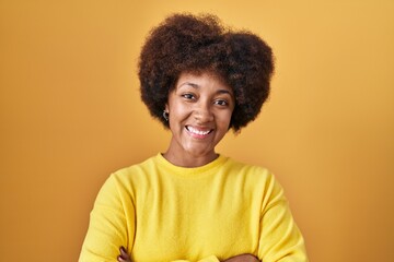 Obraz na płótnie Canvas Young african american woman standing over yellow background happy face smiling with crossed arms looking at the camera. positive person.