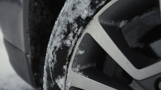 Rotating wheels of car, spinning tire by untreated from snow country road with deep snowdrifts in winter. SUV vehicle struggling to gain traction on winter road spews up snowy pieces