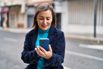 Middle age woman business executive using smartphone at street