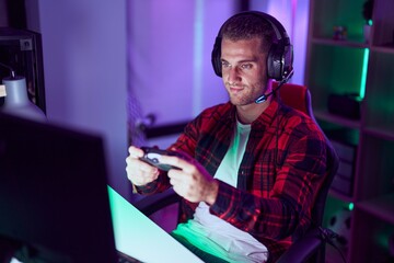 Young caucasian man streamer playing video game using joystick at gaming room