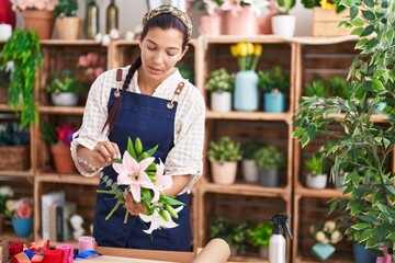 Young beautiful hispanic woman florist holding bouquet of flowers at florist