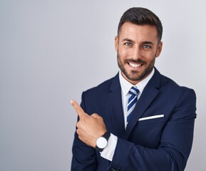 Handsome hispanic man wearing suit and tie cheerful with a smile on face pointing with hand and...