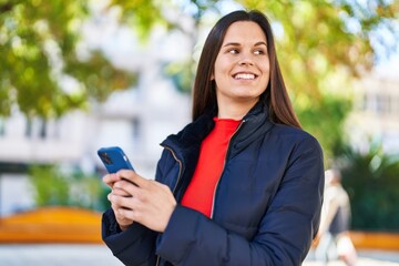 Young beautiful hispanic woman smiling confident using smartphone at park