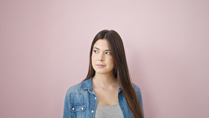 Fototapeta premium Young beautiful hispanic woman looking to the side with serious expression over isolated pink background