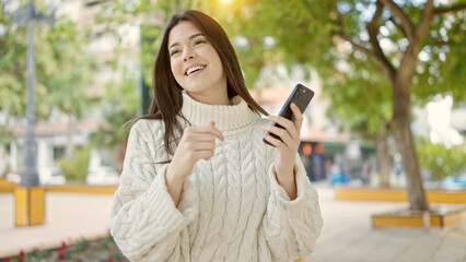 Young beautiful hispanic woman smiling confident using smartphone at park
