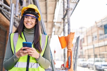 Young beautiful hispanic woman architect smiling confident using smartphone at street