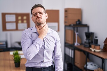 Young hispanic man at the office touching painful neck, sore throat for flu, clod and infection