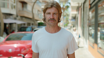 Young blond man with relaxed expression standing at street