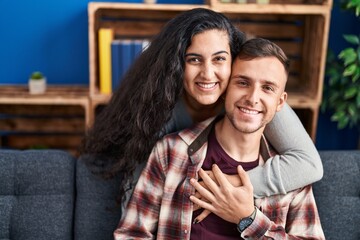 Fototapeta premium Man and woman couple hugging each other sitting on sofa at home