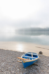blue rowing boat on sylvenstein lake shore. foggy morning scenery