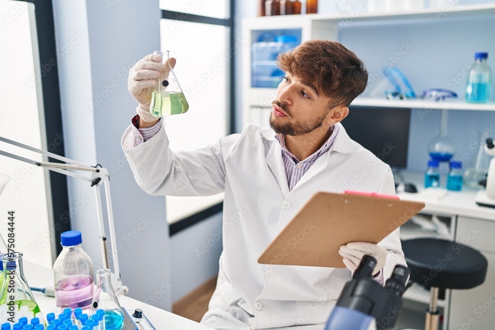 Poster Young arab man scientist measuring liquid reading report at laboratory