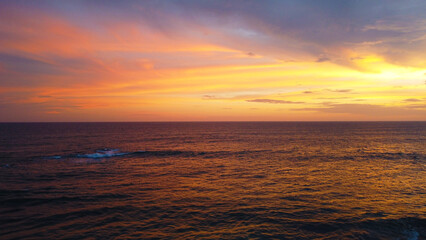 Aerial view of the sunset in an orange sky with clouds. Beautiful background for tourism and advertising. Tropical coast
