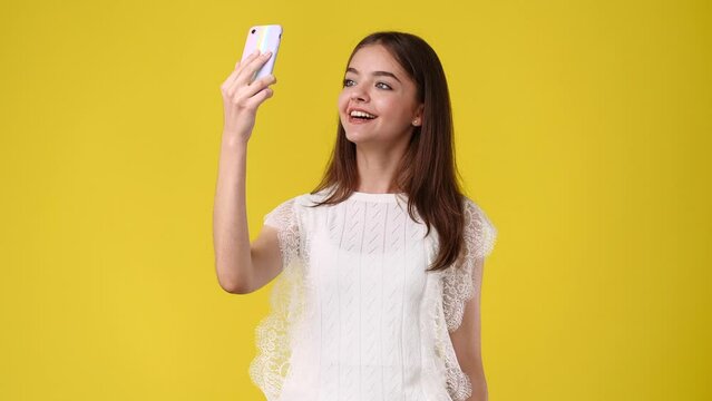 4k video of beautiful girl making selfie on yellow background.