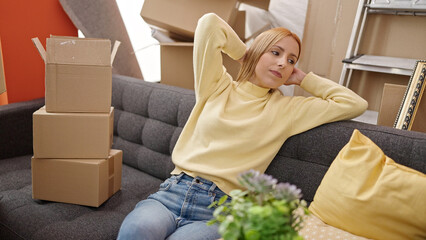 Young blonde woman relaxing on sofa at new home