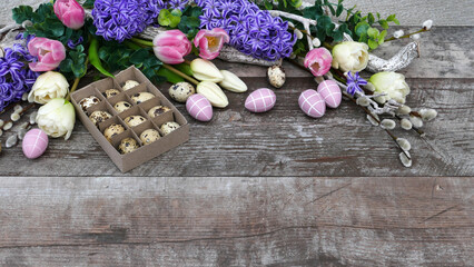 Obraz na płótnie Canvas Blumenarrangement mit Ostereiern auf rustikalem Holz Hintergrund mit Platz für Text.