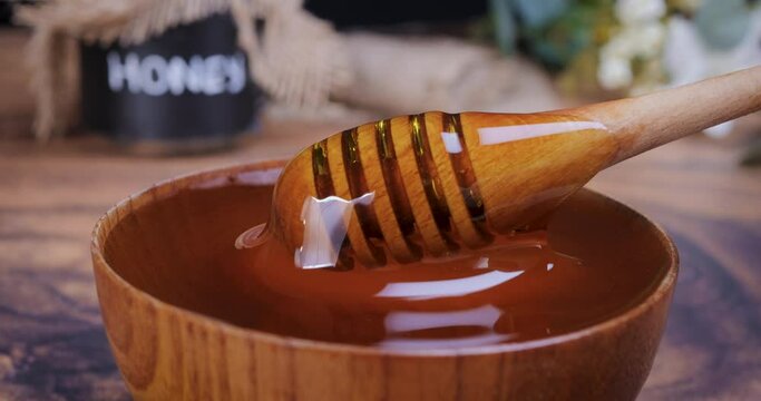 Honey spoon coming out of the bowl full of honey in slow motion. Honey contains many nutrients, antioxidants, improves heart health, wound care, offers antidepressant and anti-anxiety benefits. 4k