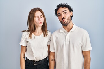 Fototapeta premium Young couple wearing casual clothes standing together making fish face with lips, crazy and comical gesture. funny expression.