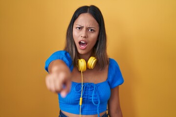 Hispanic young woman standing over yellow background pointing displeased and frustrated to the camera, angry and furious with you