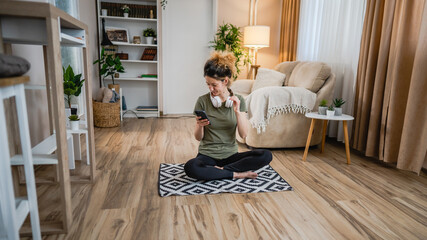 One woman sit on the floor at home with headphones and smartphone
