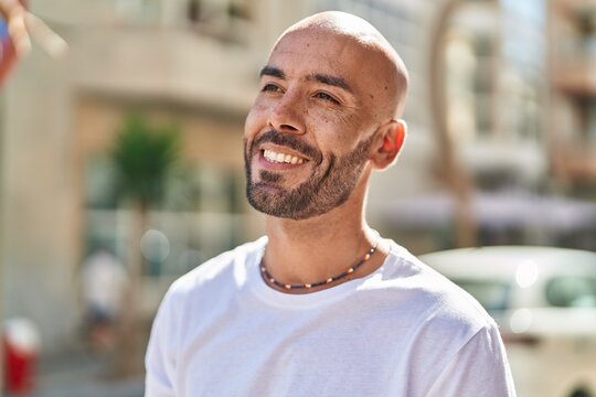 Young bald man smiling confident looking to the side at street