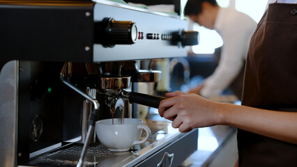 Barista water white coffee mug is a mug for hot coffee, put under coffee machine which is distilling coffee water, flows through handle coffee maker, Into a coffee mug ready to serve.