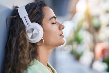 Young beautiful hispanic woman listening to music at street