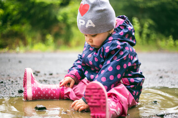 Baby girl plays in the puddle