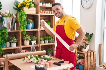 Young hispanic man florist smiling confident holding gift lace at florist