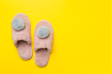 Soft pink slippers on color background, top view