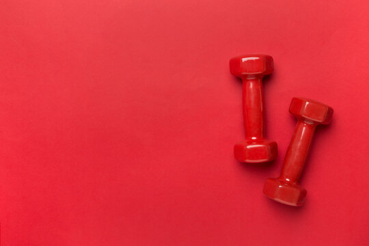Red dumbbells on color background, top view