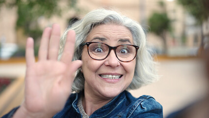 Middle age woman with grey hair smiling confident having video call at park