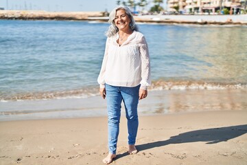 Middle age woman smiling confident standing at seaside