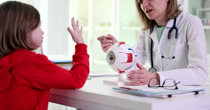 Ophthalmologist teaches anatomy of eye in clinic to girl child