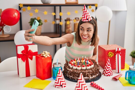 Young beautiful hispanic woman celebrating birthday make selfie by smartphone at home