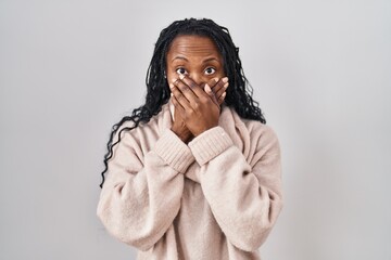 African woman standing over white background shocked covering mouth with hands for mistake. secret...