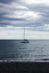 A vertical picture of a boat floating on water in the middle of an ocean