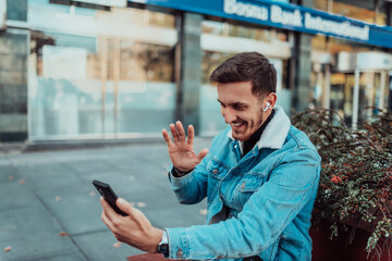 A gappy student sitting in a park using a smartphone and wireless headphones