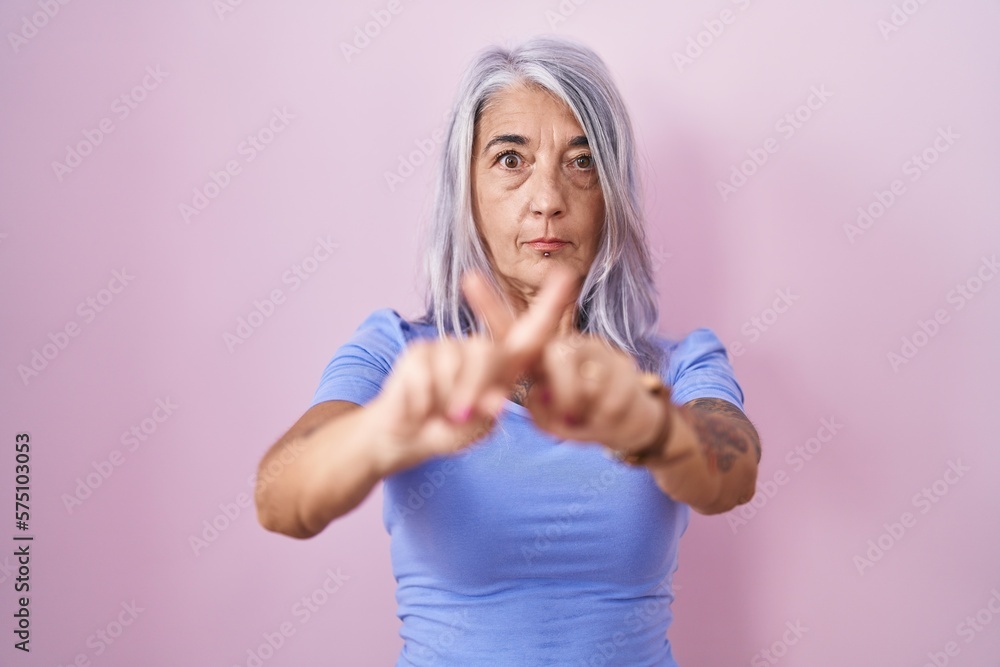 Sticker middle age woman with tattoos standing over pink background rejection expression crossing fingers do