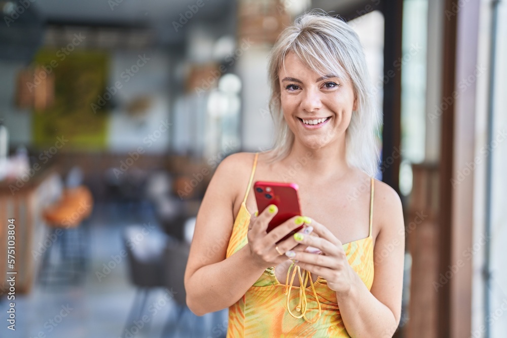 Poster Young blonde woman smiling confident using smartphone at street