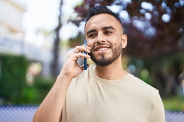 Young hispanic man smiling confident talking on the smartphone at park