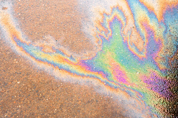 Oil slick on the asphalt road background. Rainbow gasoline oil spill on the pavement as a texture or background.