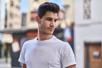 Young hispanic man looking to the side with serious expression at street